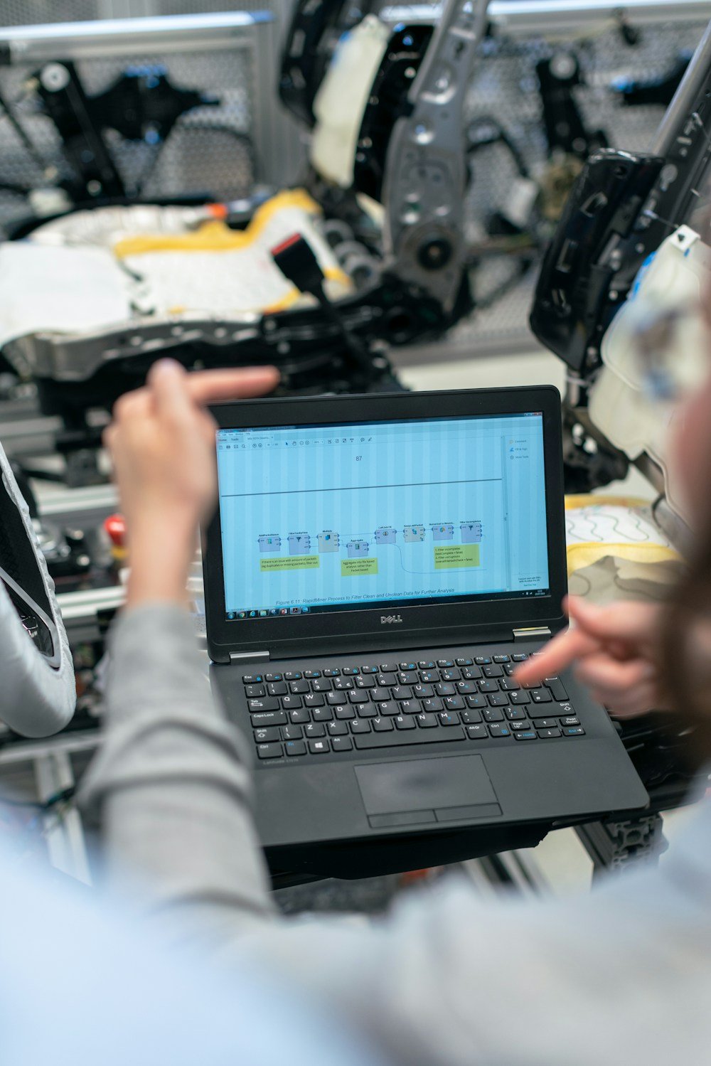 An engineer reviewing data on a laptop beside equipment